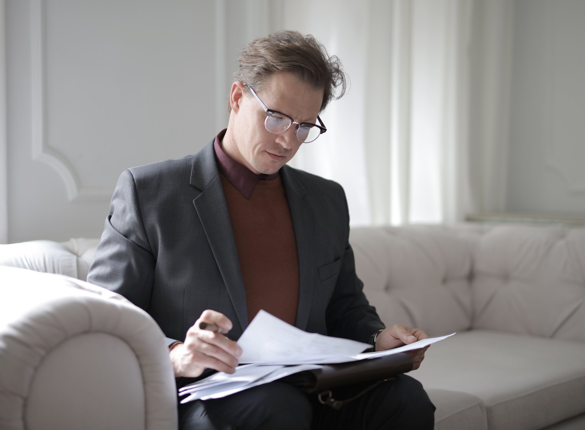 Classy executive male reading papers on couch